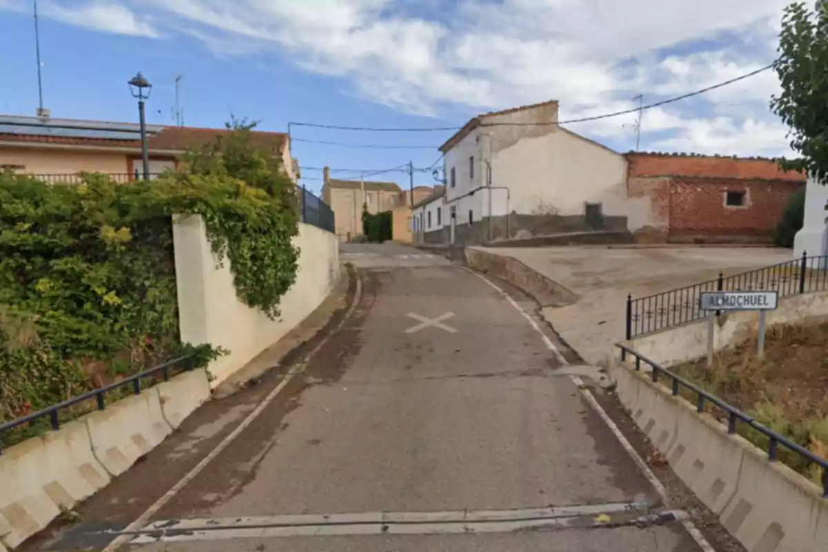 Una calle estrecha en un pueblo con casas de paredes blancas y un cartel que indica Una calle estrecha en un pueblo con casas de paredes blancas y un cartel que indica