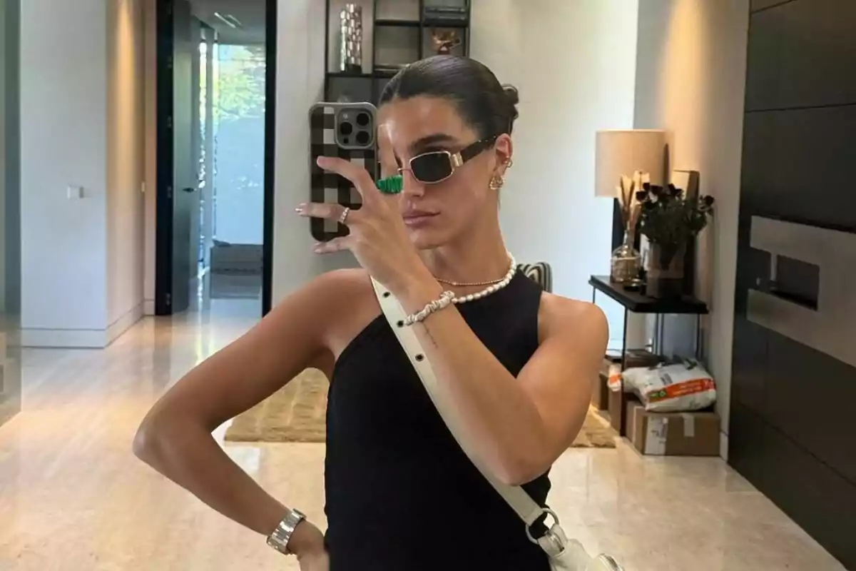 A person with sunglasses takes a selfie in front of a mirror in a modern room. A person with sunglasses takes a selfie in front of a mirror in a modern room.