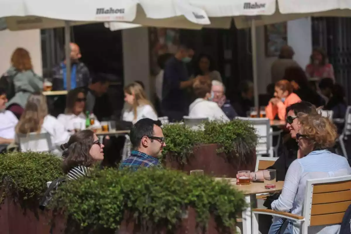 Imatge de diverses persones assegudes a la terrassa d'un bar a la tardor