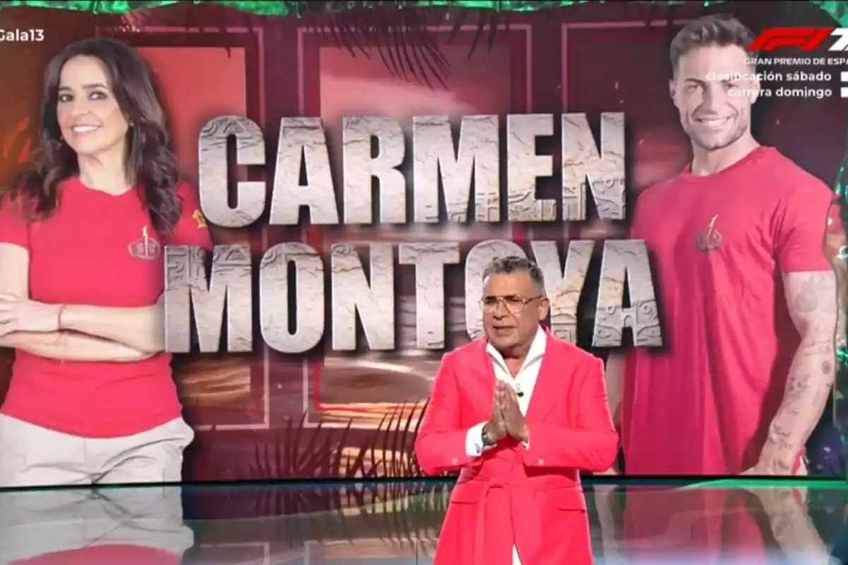 Un presentador amb vestit rosa està dret davant d’una pantalla que mostra una dona i un home amb samarretes vermelles i el text CARMEN MONTOYA en gran. Un presentador amb vestit rosa està dret davant d’una pantalla que mostra una dona i un home amb samarretes vermelles i el text CARMEN MONTOYA en gran.
