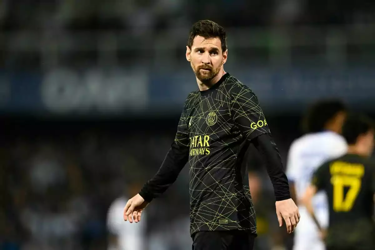 Un jugador de futbol amb uniforme negre i detalls daurats és al camp durant un partit. Un jugador de futbol amb uniforme negre i detalls daurats és al camp durant un partit.