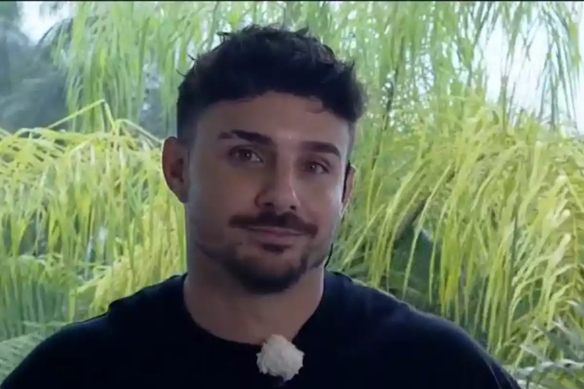 Manuel González con barba y cabello oscuro está frente a un fondo de plantas verdes.