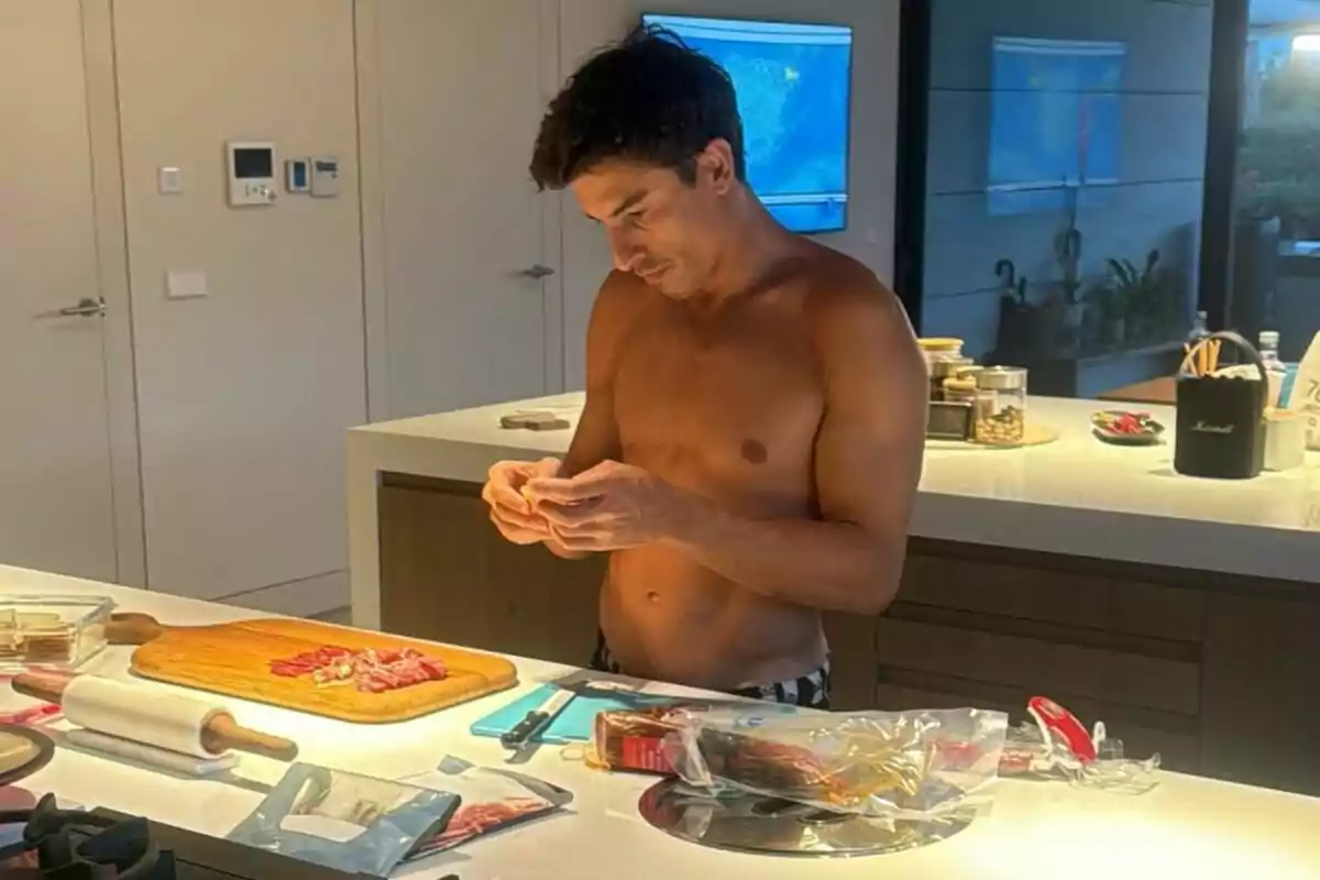 A jerseyless man is in a modern kitchen preparing food on a lit countertop, surrounded by utensils and food. A jerseyless man is in a modern kitchen preparing food on a lit countertop, surrounded by utensils and food.