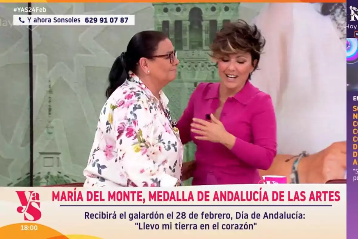 Two people interact on a television show, one wearing a floral jersey and the other a pink dress, while at the bottom of the image a text highlights an award for María del Monte. Two people interact on a television show, one wearing a floral jersey and the other a pink dress, while at the bottom of the image a text highlights an award for María del Monte.
