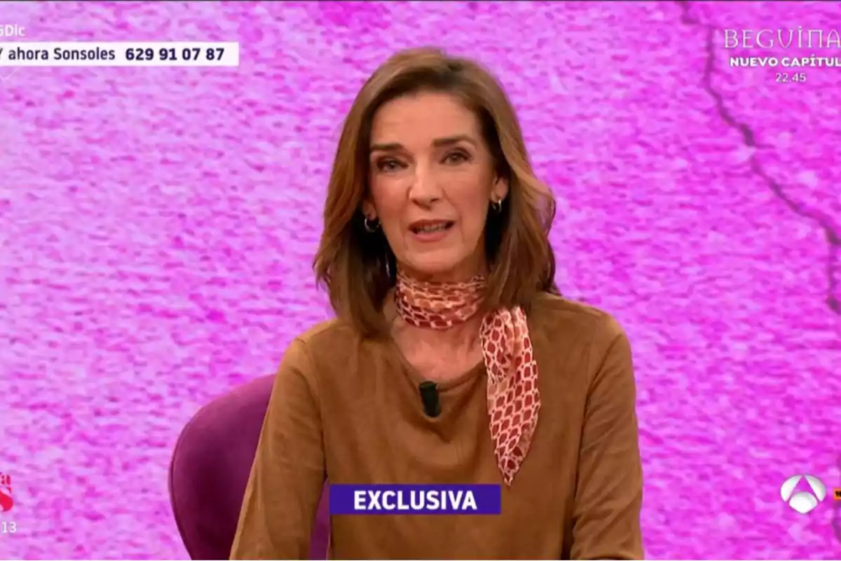 Dona en un programa de televisió amb fons rosa i text 