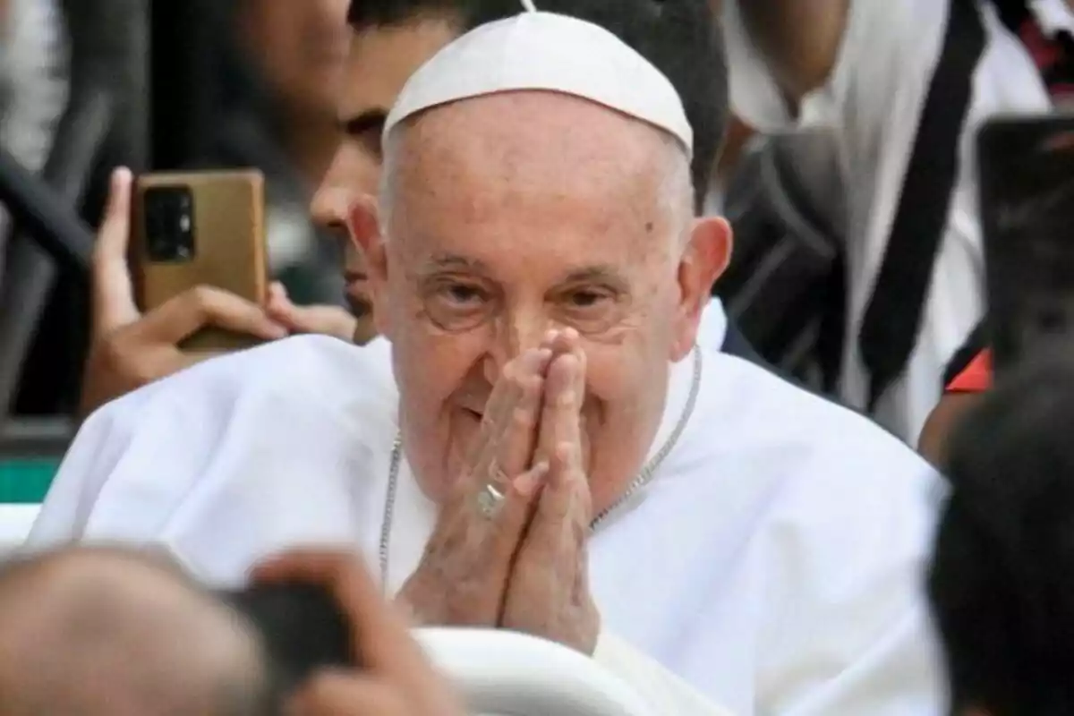 Close-up of Pope Francis with his hands in a prayer gesture.