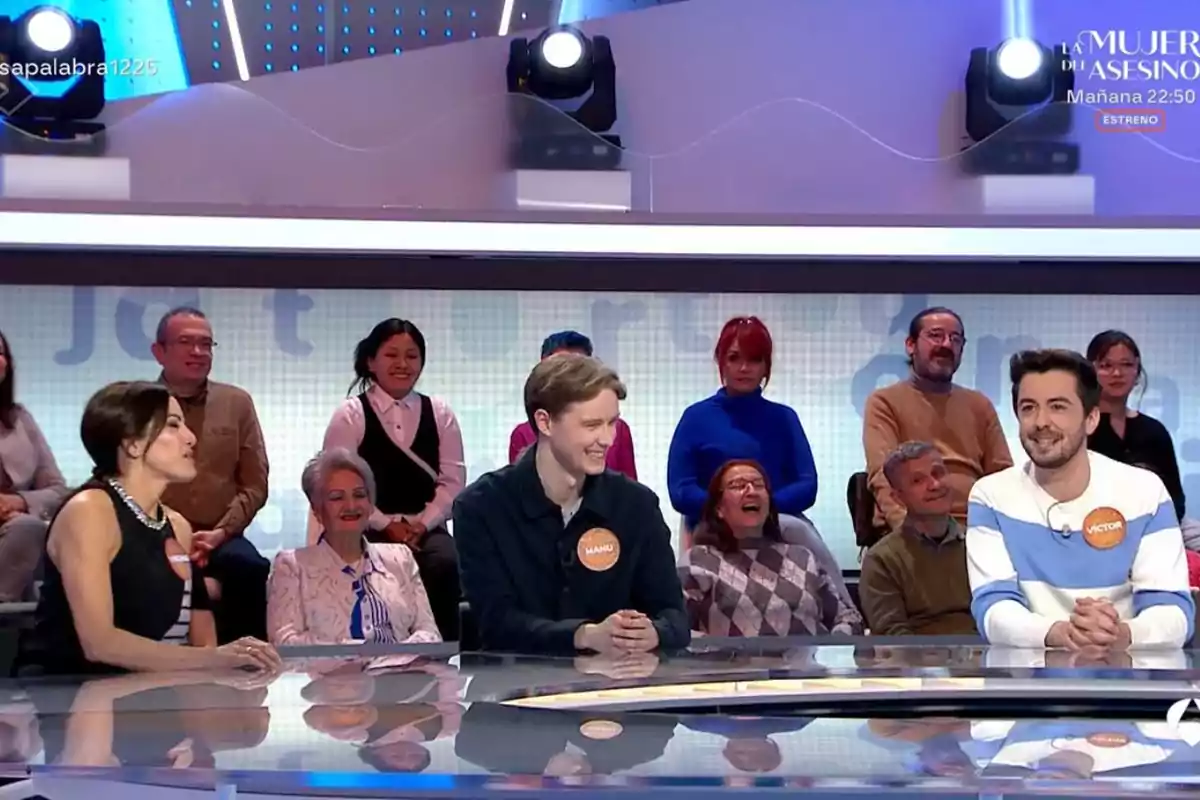 Un grup de persones participa en un programa de televisió, asseguts darrere d'una taula en un estudi amb públic al fons. Un grup de persones participa en un programa de televisió, asseguts darrere d'una taula en un estudi amb públic al fons.