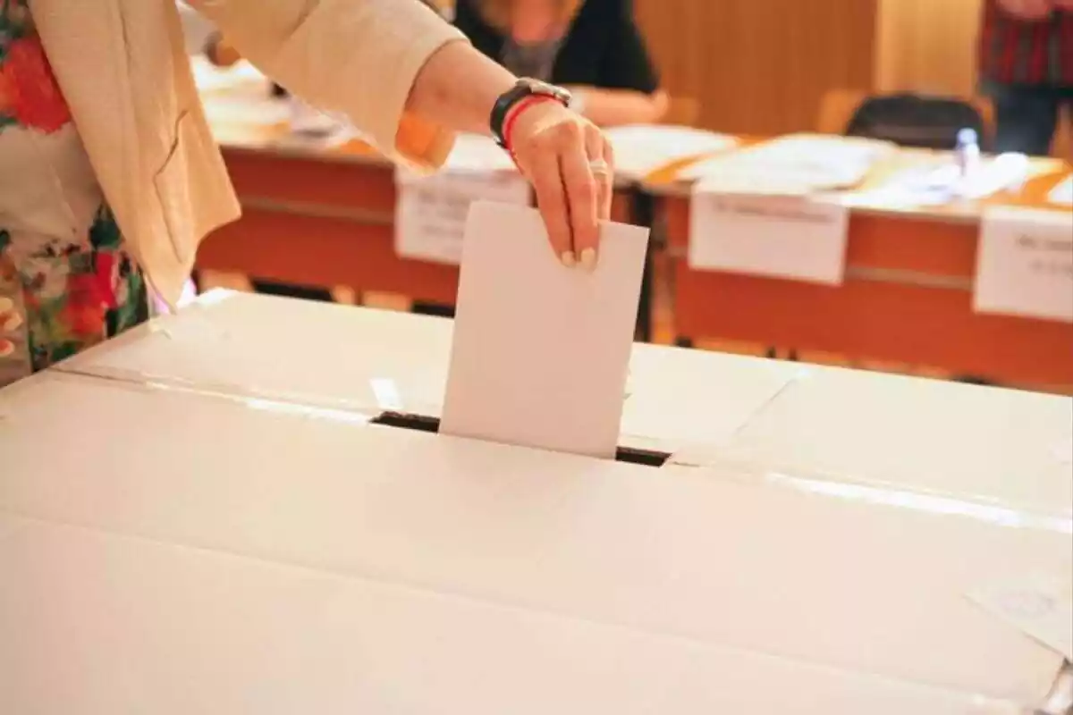 Imatge d'una persona introduint una carta d'una votació en una urna