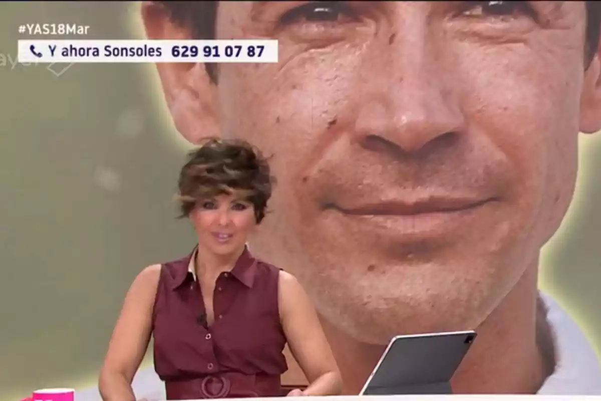 A TV host is in a studio with a background image showing a close-up of a male face, while a phone number and a hashtag appear in the top left corner. A TV host is in a studio with a background image showing a close-up of a male face, while a phone number and a hashtag appear in the top left corner.