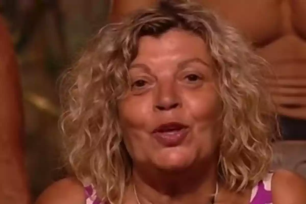 Dona de cabell ros arrissat i curt amb expressió somrient en un entorn interior