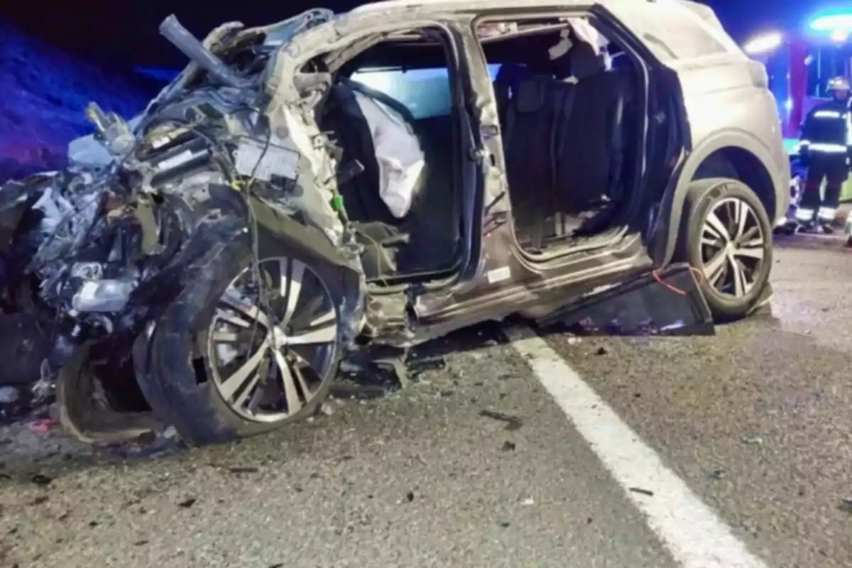 Vehicle SUV greument danyat després d’un accident a la carretera amb presència de serveis d’emergència al fons Vehicle SUV greument danyat després d’un accident a la carretera amb presència de serveis d’emergència al fons