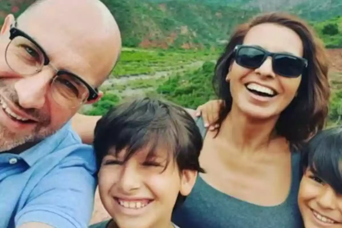 Una família somrient es fa una selfie a l'aire lliure amb un paisatge verd de fons. Una família somrient es fa una selfie a l'aire lliure amb un paisatge verd de fons.