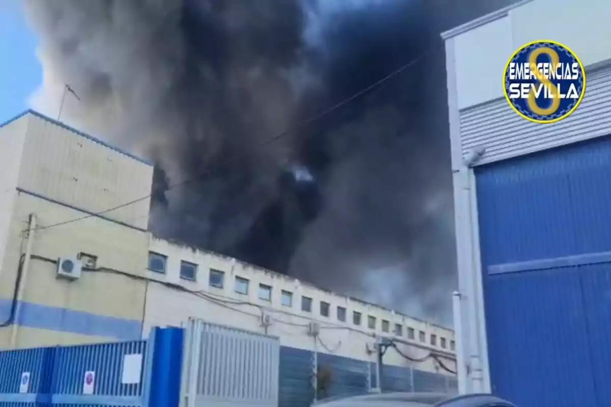 Un edifici industrial amb fum negre sortint del sostre i un logotip de Un edifici industrial amb fum negre sortint del sostre i un logotip de