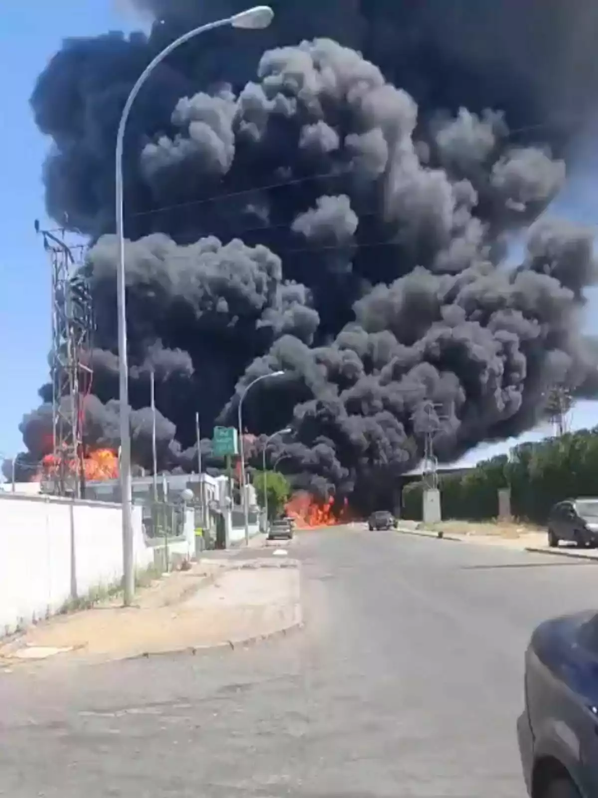 Una gran columna de fum negre s'eleva des d'un incendi en una zona urbana de Sevilla, amb flames visibles i vehicles estacionats al carrer proper. Una gran columna de fum negre s'eleva des d'un incendi en una zona urbana de Sevilla, amb flames visibles i vehicles estacionats al carrer proper.