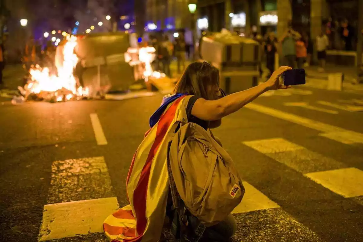 Una manifestant comença es fa un selfie amb un contenidor que es crema durant una manifestació pel referèndum de l'1-O a Catalunya,