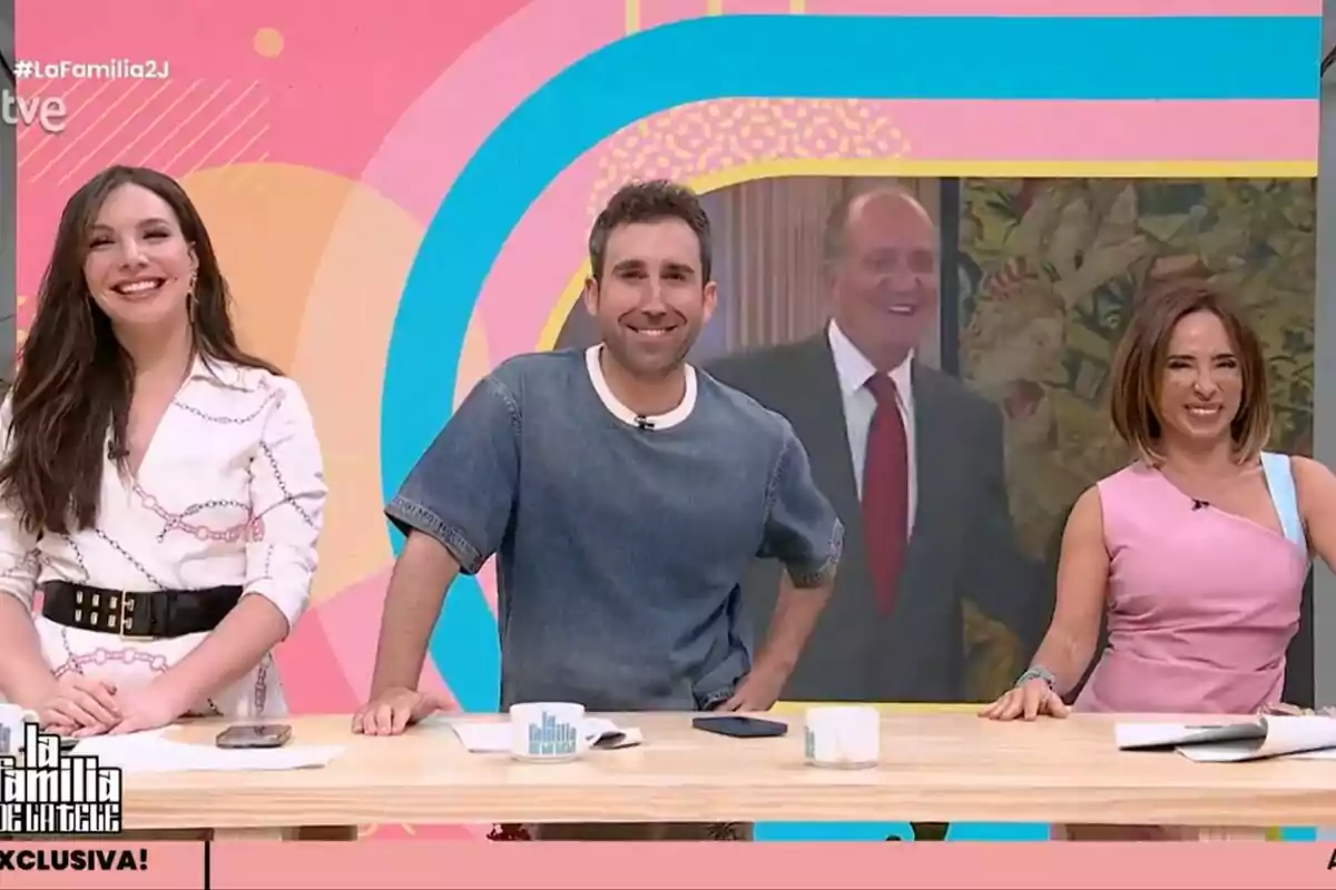 Inés Hernand, Aitor Albizua i María Patiño somriuen en un plató de televisió de La Família de la Tele acolorit amb una pantalla al fons que mostra un home gran elegantment vestit. Inés Hernand, Aitor Albizua i María Patiño somriuen en un plató de televisió de La Família de la Tele acolorit amb una pantalla al fons que mostra un home gran elegantment vestit.