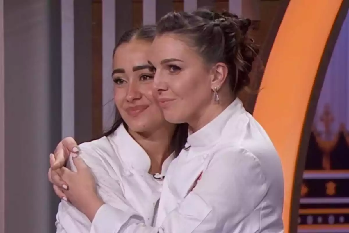 Inés Hernand i Marina Rivers amb jaquetes blanques de xef s'abracen i somriuen en un ambient interior a MasterChef Celebrity.