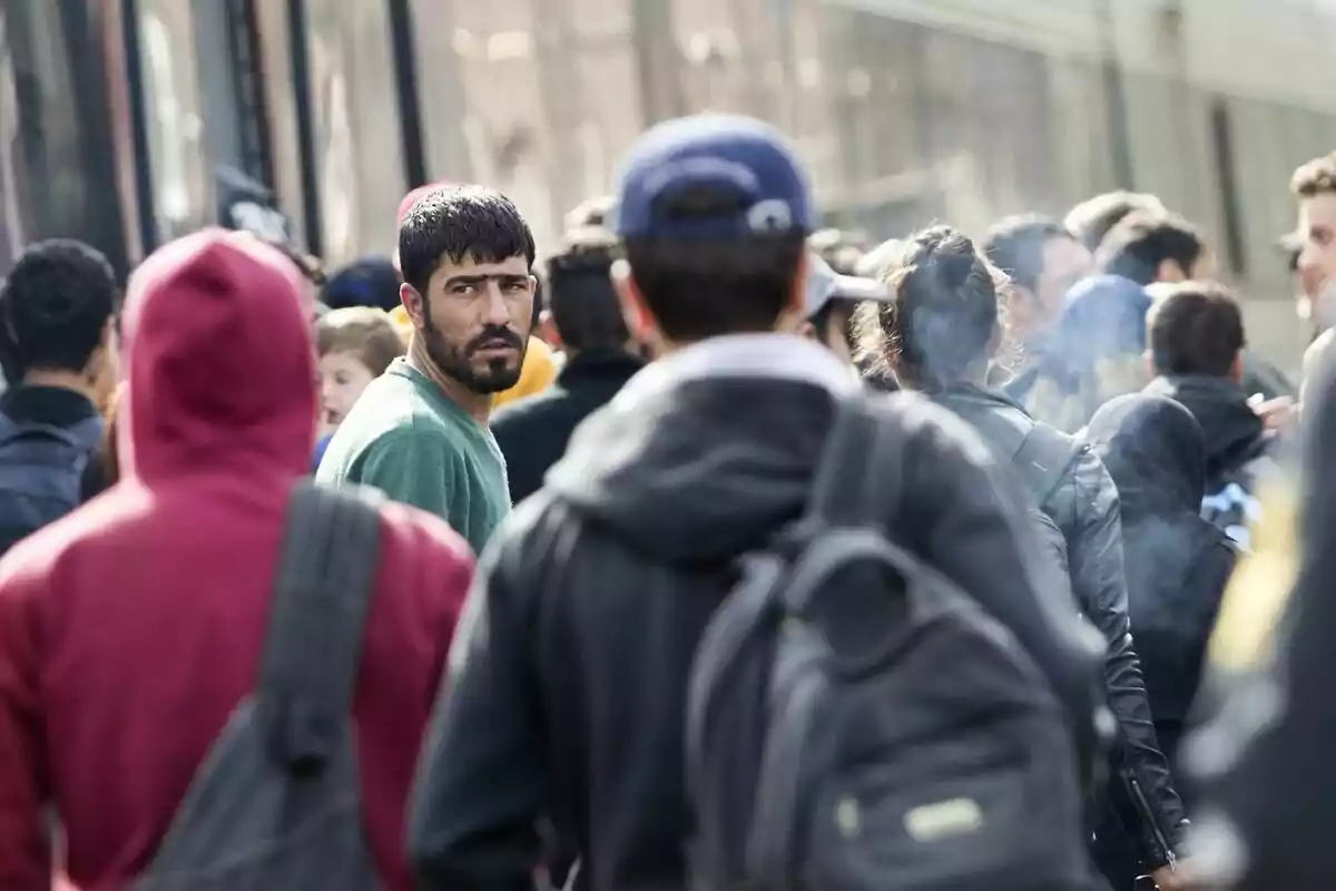 Un grupo de personas camina por una calle concurrida, con un hombre mirando hacia atrás.