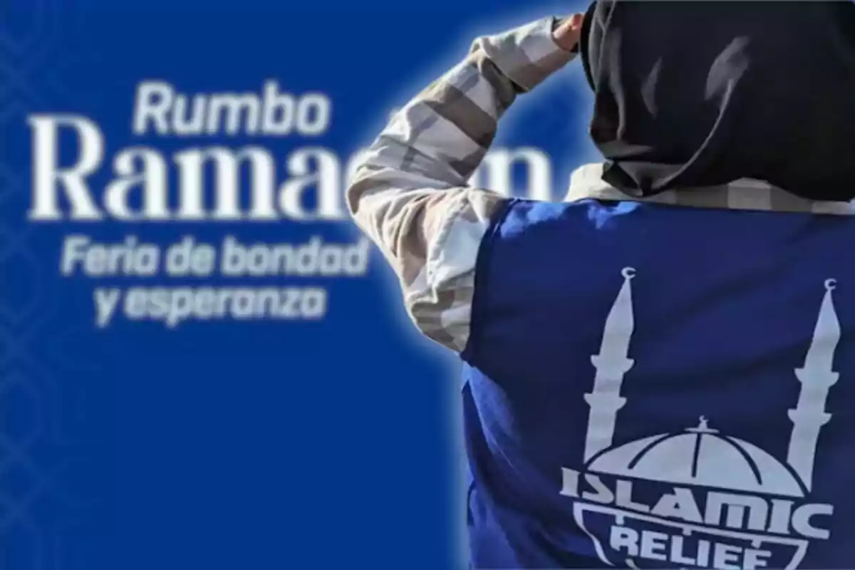 A person with an "Islamic Relief" vest in front of a sign that says "Heading Ramadan Fair of Kindness and Hope."