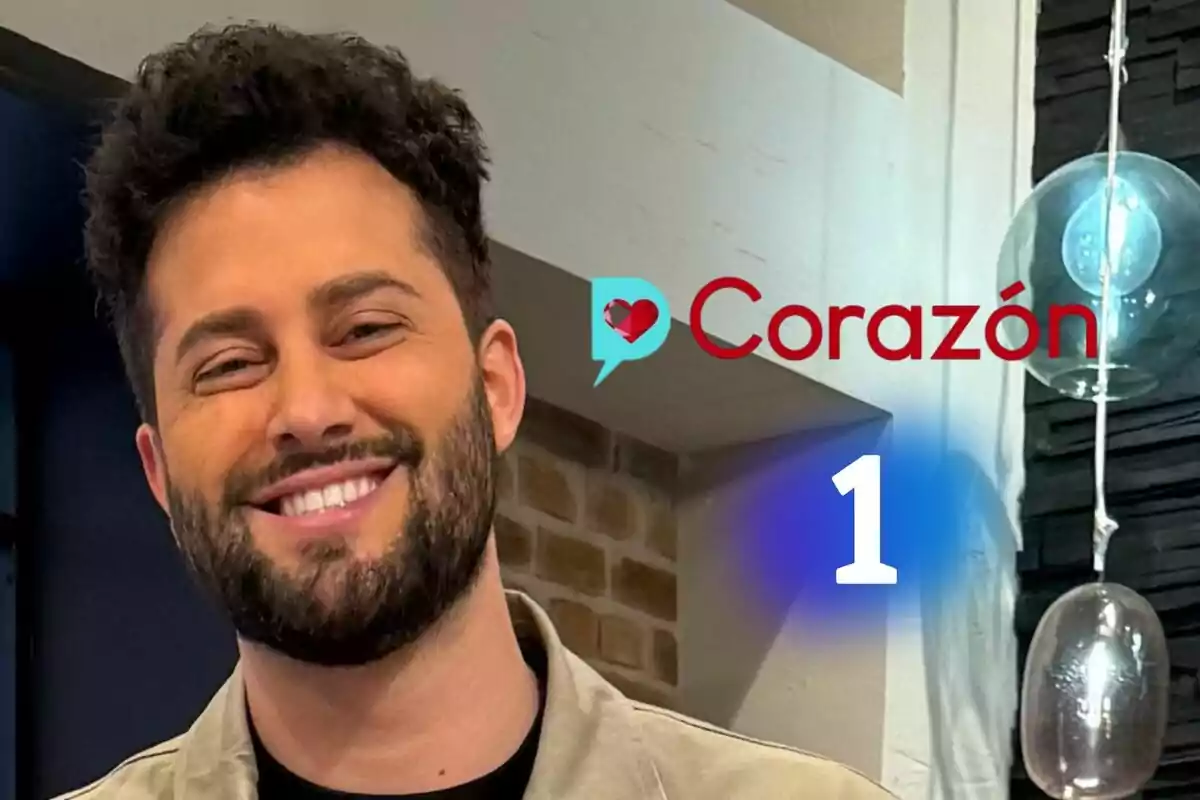 Javi de Hoyos somrient amb barba i cabell arrissat en un estudi amb el logotip de D Corazón i el logotip de La 1 al fons