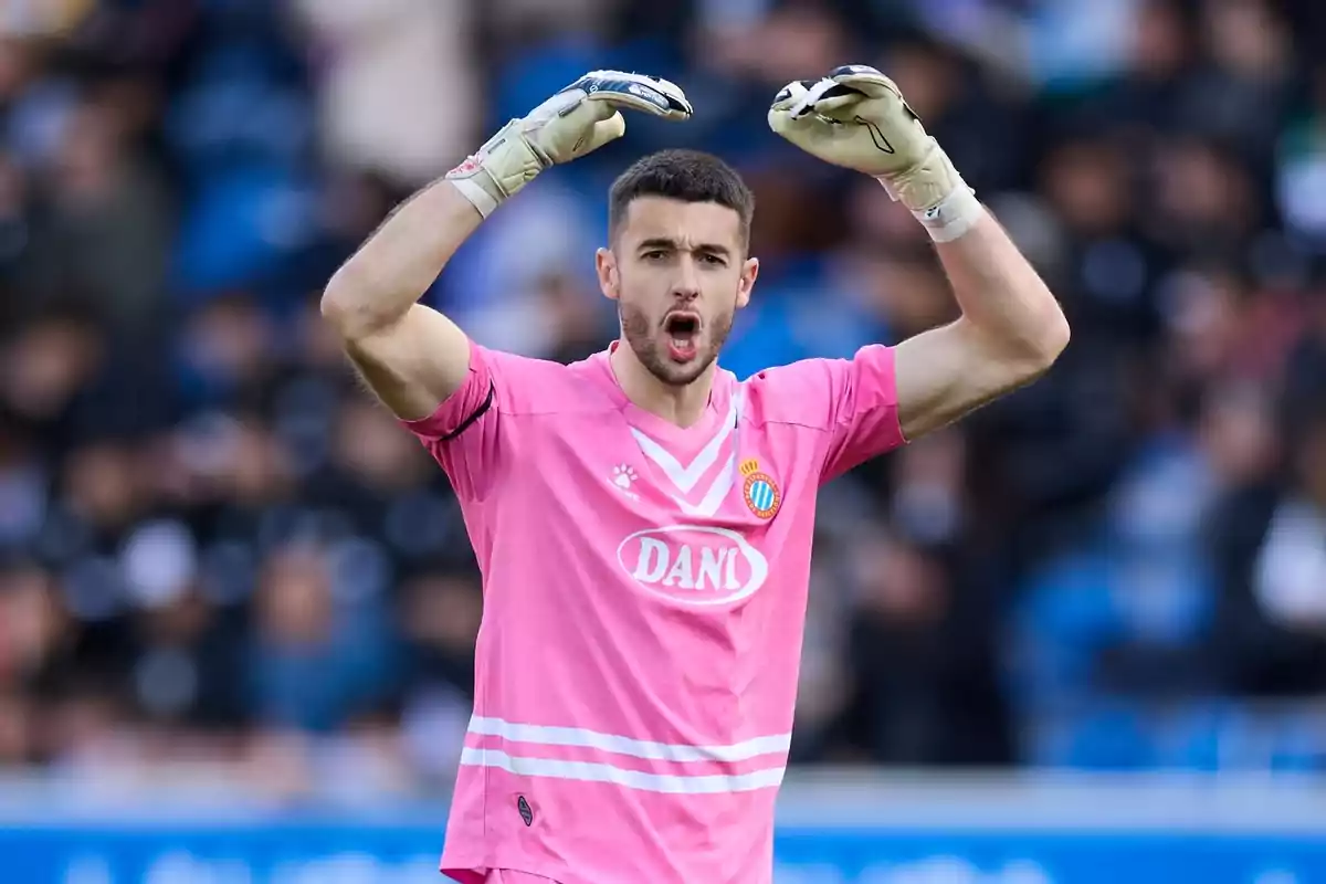 A player in a pink uniform and gloves raises his arms in a stadium. A player in a pink uniform and gloves raises his arms in a stadium.