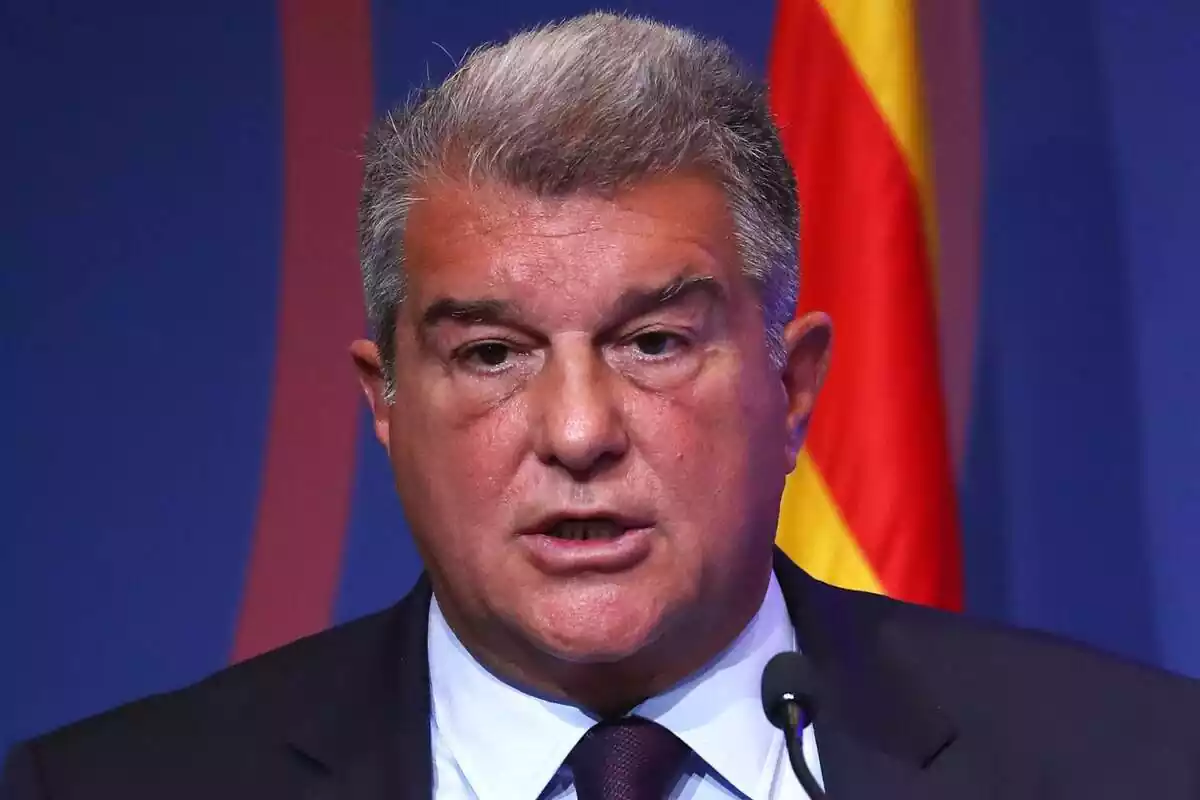 Joan Laporta amb expressió seriosa en un primer pla amb una bandera de fons