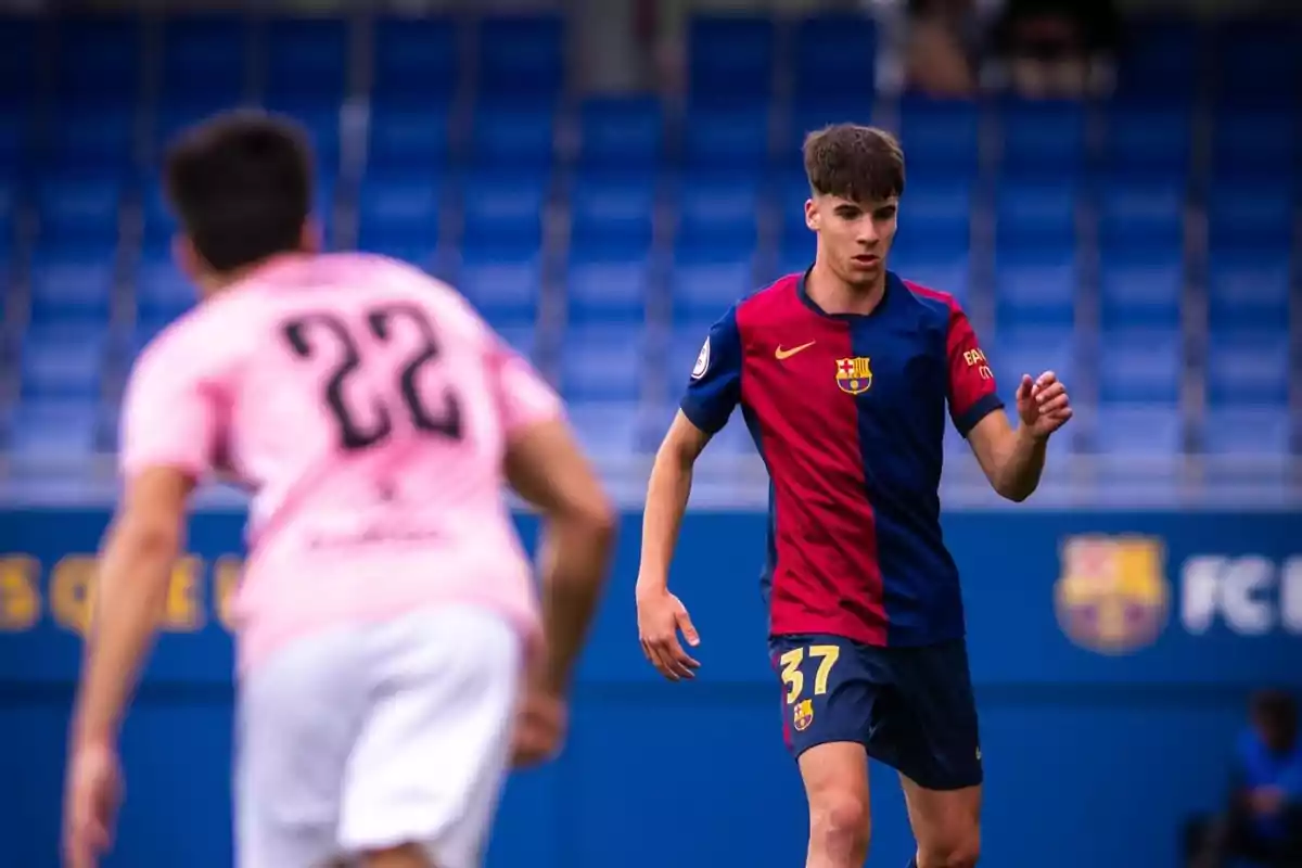 Barcelona player wearing number 37 on the blue and red uniform during a soccer match against an opponent in a pink jersey with number 22 in a stadium with blue stands. Barcelona player wearing number 37 on the blue and red uniform during a soccer match against an opponent in a pink jersey with number 22 in a stadium with blue stands.