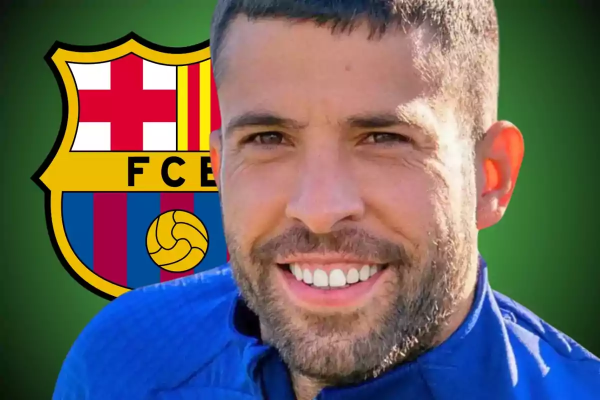 A smiling man in a blue t-jersey in front of the FC Barcelona crest.