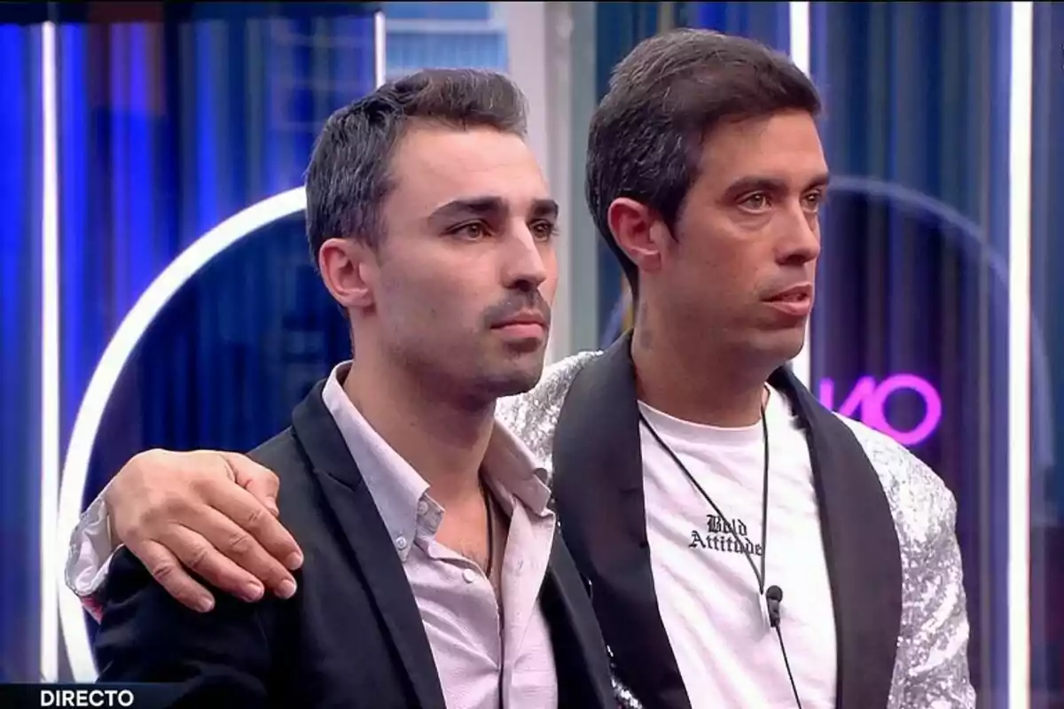 Jorge i Javier dret a la casa de Gran Hermano amb llums de neó al fons, un amb el braç sobre l'espatlla de l'altre.