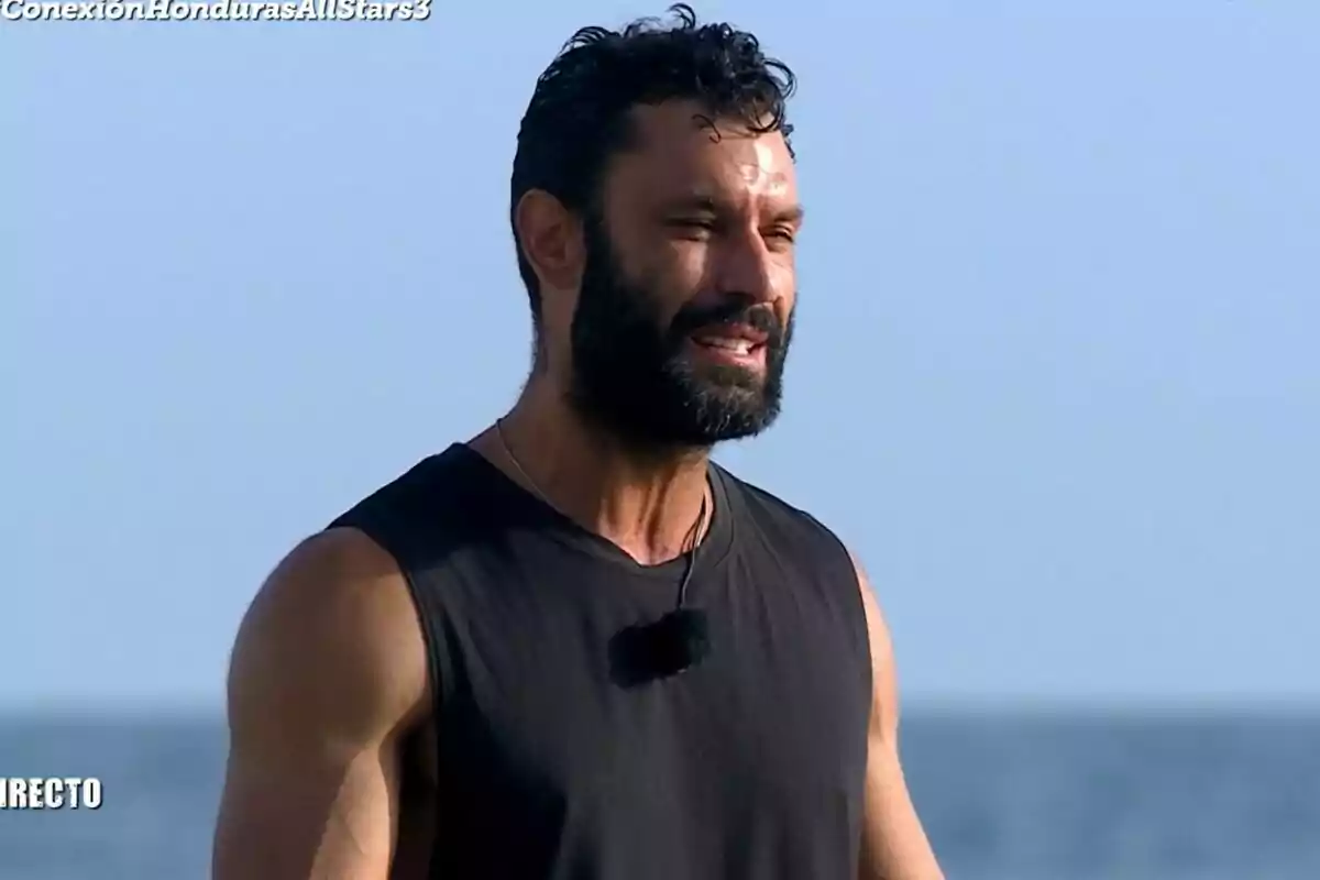 Fotografía de Jorge Pérez con barba y cabello rizado, vistiendo una camiseta sin mangas negra, con el cielo azul de fondo en el puente de las emociones de Supervivientes