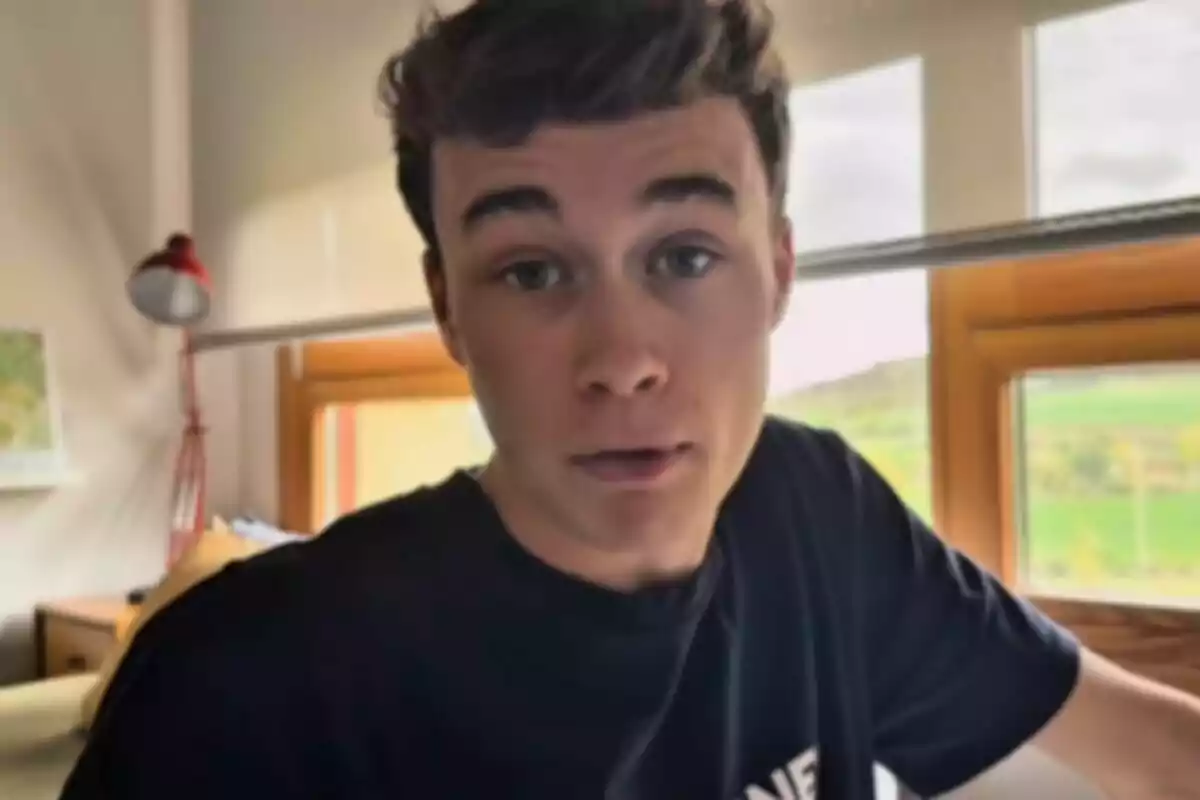 Jorge Rey, aficionat a la meteorologia, amb cabell fosc i samarreta negra està en una habitació amb una làmpada vermella i una finestra al fons.