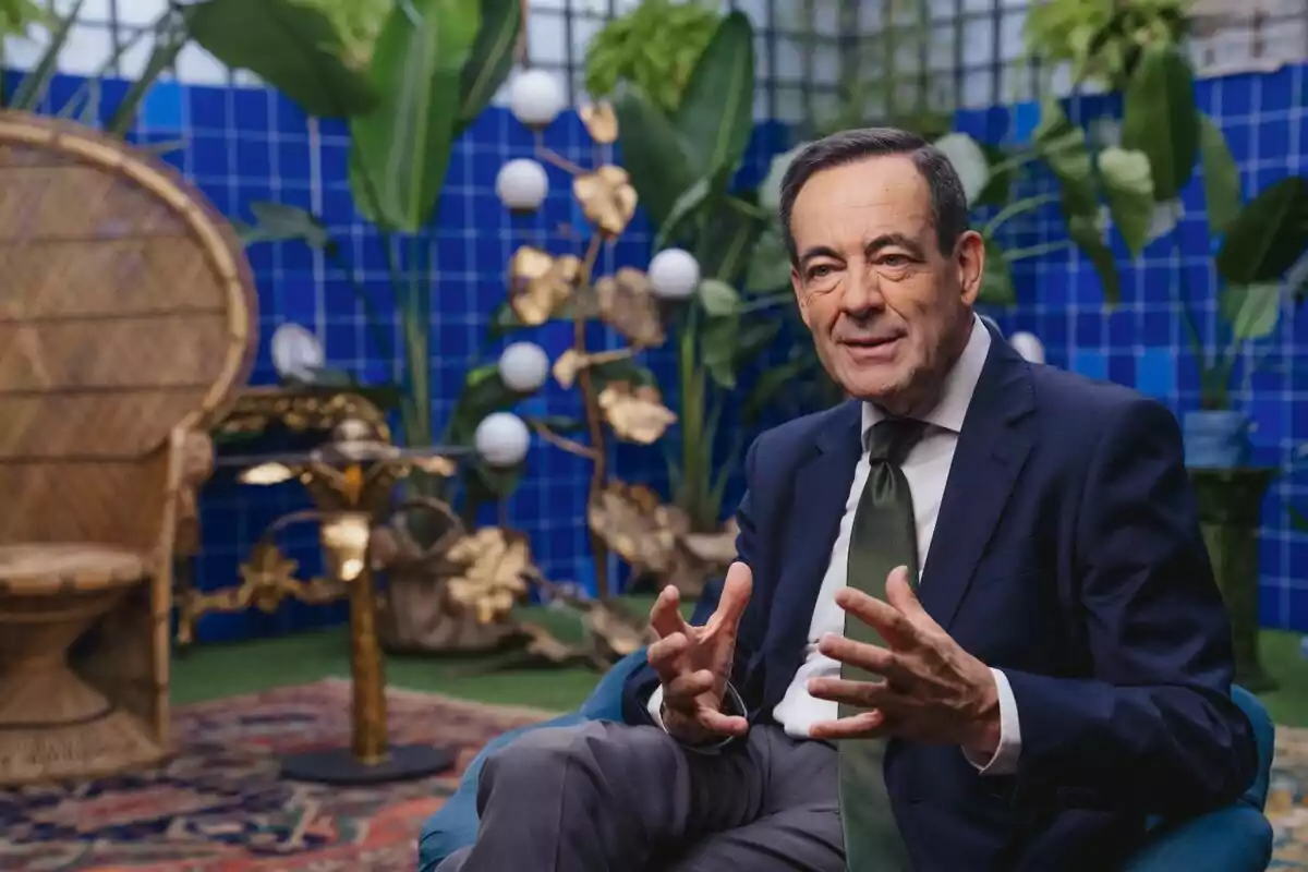 José Bono amb vestit fosc i corbata verda està assegut en un sofà blau en un entorn decorat amb plantes i un fons de rajoles blaves a la sèrie documental 'Súper Sara'. José Bono amb vestit fosc i corbata verda està assegut en un sofà blau en un entorn decorat amb plantes i un fons de rajoles blaves a la sèrie documental 'Súper Sara'.