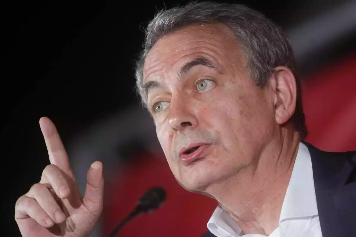 Primer pla de José Luis Rodríguez Zapatero parlant en un míting i assenyalant cap amunt amb el dit índex