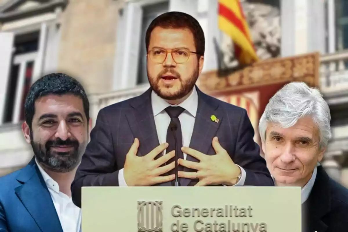 Un home en vestit parla en un faristol amb l'emblema de la Generalitat de Catalunya mentre dues persones són al seu costat i una bandera catalana es veu al fons.