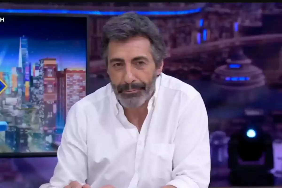 Juan del Val amb barba i camisa blanca està assegut davant d'un fons colorit i urbà a 'El Hormiguero'.