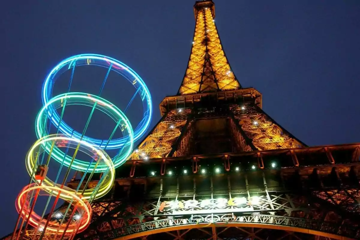 La Torre Eiffel iluminada por la noche con anillos de luces de colores por los Juegos Olimpicos en primer plano.