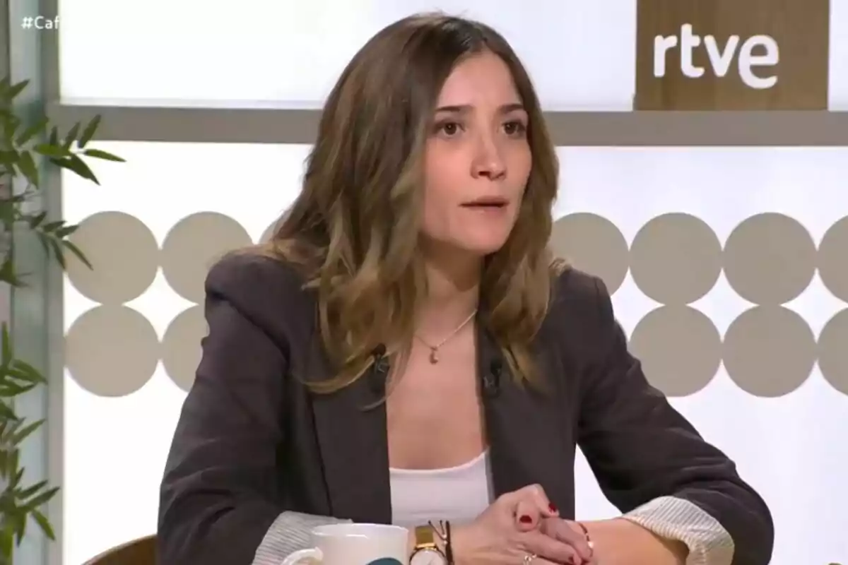 Una mujer con cabello castaño y chaqueta oscura está sentada en un estudio de televisión con el logo de RTVE visible al fondo.