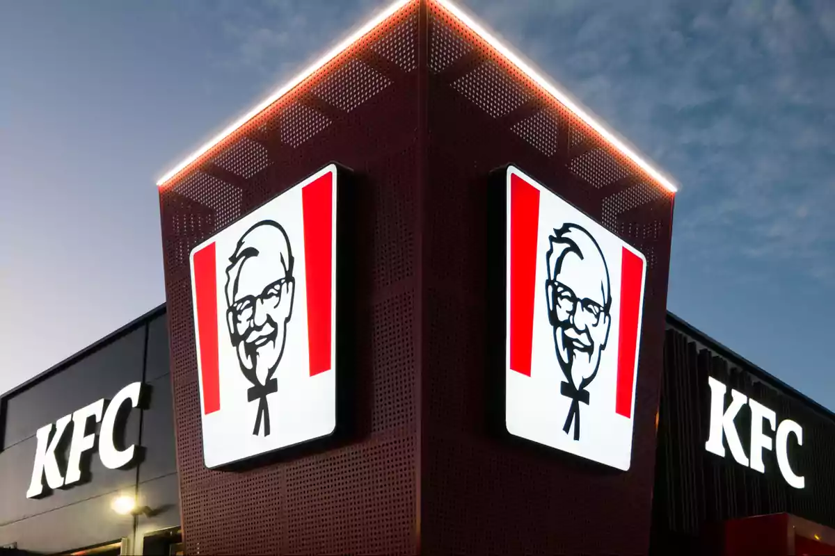 Un edificio de KFC con el logotipo iluminado en la fachada al anochecer.