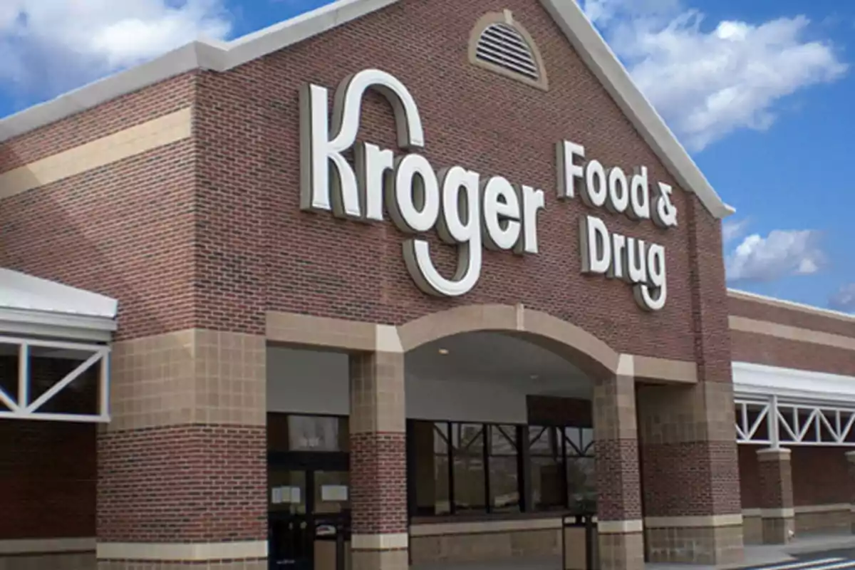 Façana d'una botiga amb un rètol gran que diu "Kroger Food & Drug" en un edifici de maó sota un cel blau amb núvols.