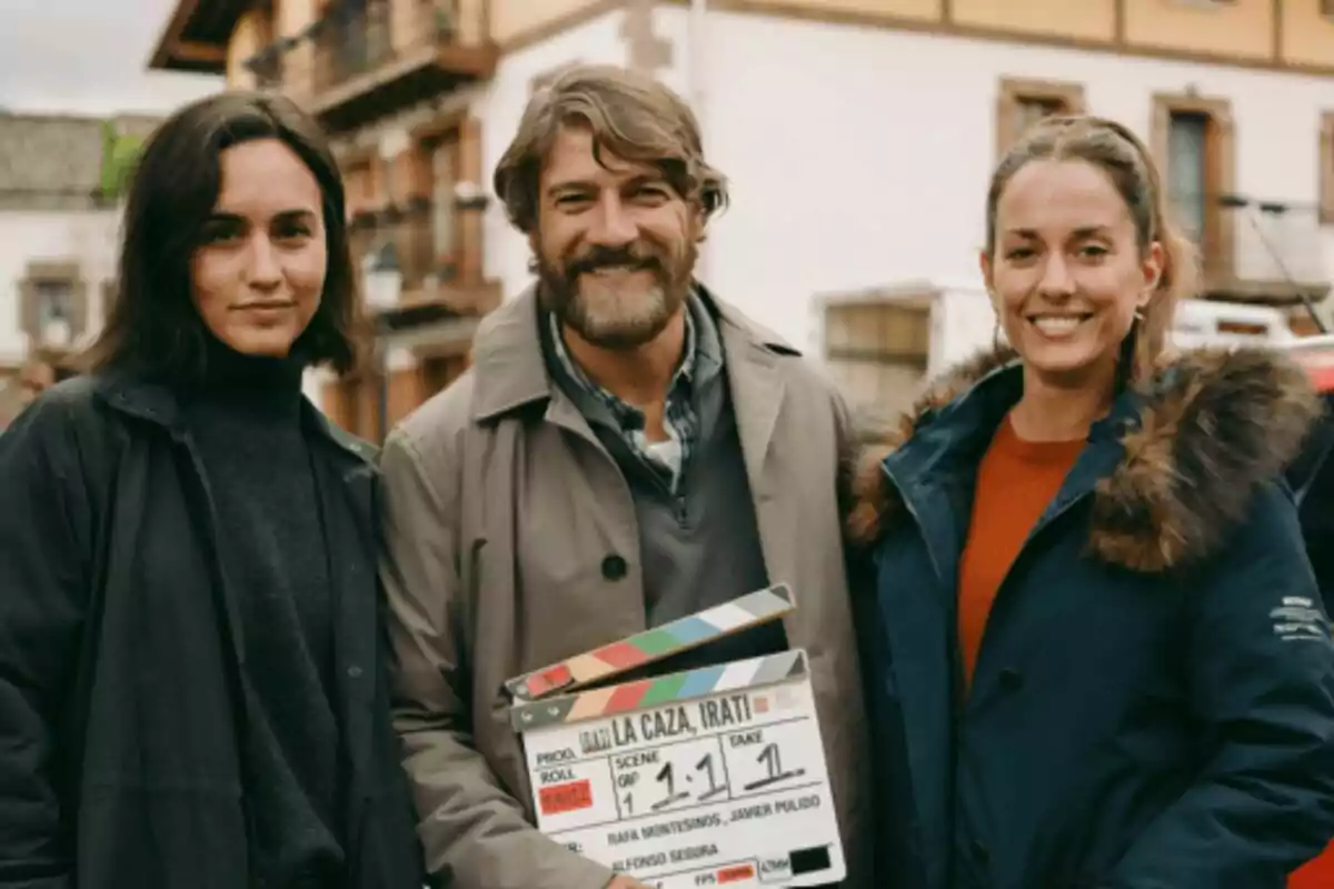 Megan Montaner, Félix Gómez i Silvia Alonso somriuen a la cambra mentre sostenen una claqueta del rodatge de La Caça en un entorn urbà.