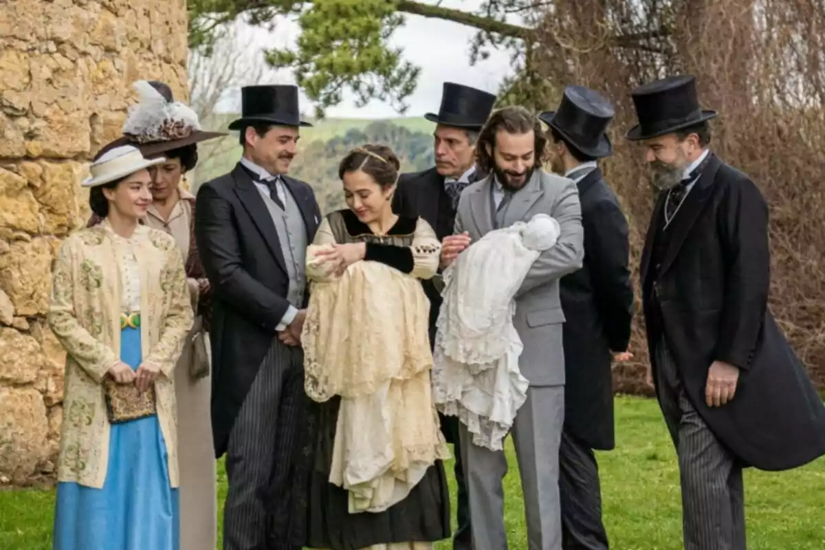 Un grup de persones vestides amb roba d’època posen a l’aire lliure mentre dues d’elles sostenen nadons embolicats amb mantes elegants. Captura de ‘La Promesa’ Un grup de persones vestides amb roba d’època posen a l’aire lliure mentre dues d’elles sostenen nadons embolicats amb mantes elegants. Captura de ‘La Promesa’