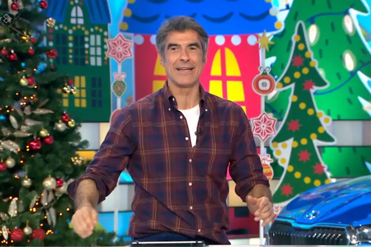 Jorge Fernández dret amb camisa a quadres en un set decorat amb motius nadalencs i un arbre de Nadal. Captura de 'La Ruleta de la Suerte'