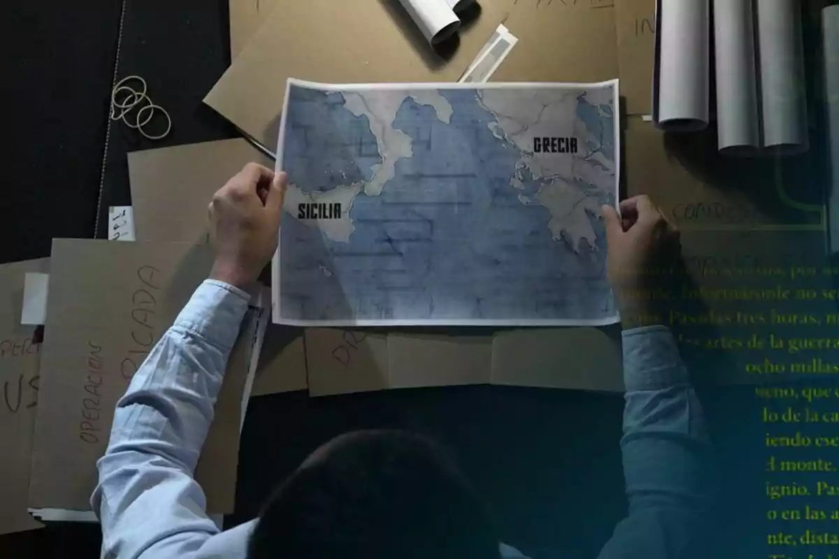 Persona observant un mapa de Sicília i Grècia sobre una taula plena de carpetes i documents de laSexta Columna.