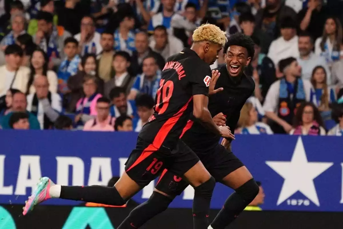 Two players celebrate a goal in a stadium full of fans. Two players celebrate a goal in a stadium full of fans.