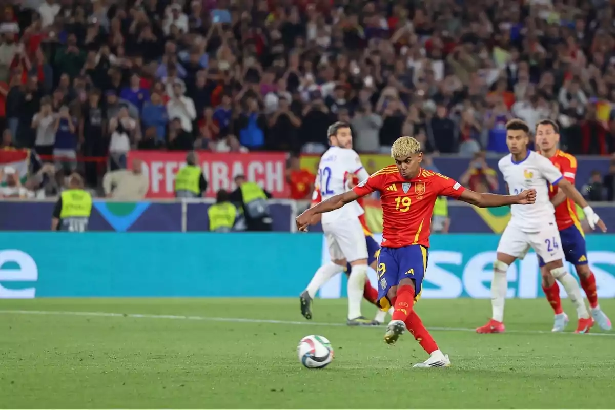 Jugador de la selecció d’Espanya xuta la pilota durant un partit de futbol contra la selecció de França amb el públic i fotògrafs al fons Jugador de la selecció d’Espanya xuta la pilota durant un partit de futbol contra la selecció de França amb el públic i fotògrafs al fons
