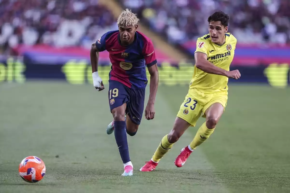 Dos jugadors de futbol competeixen per la pilota en un partit, un vesteix uniforme blau i vermell i l'altre groc. Dos jugadors de futbol competeixen per la pilota en un partit, un vesteix uniforme blau i vermell i l'altre groc.