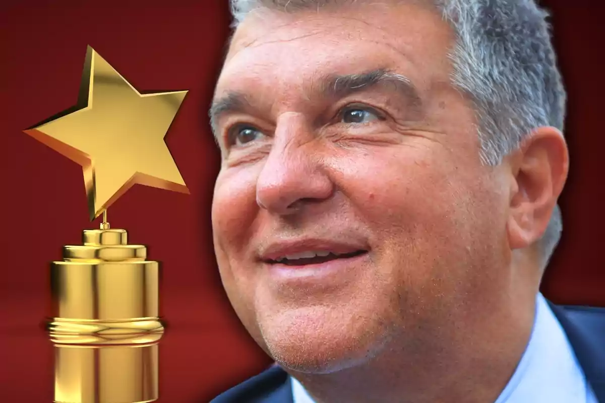 Un home somrient amb cabell canós i ulls clars, amb un trofeu daurat en forma d'estrella al costat, sobre un fons vermell.