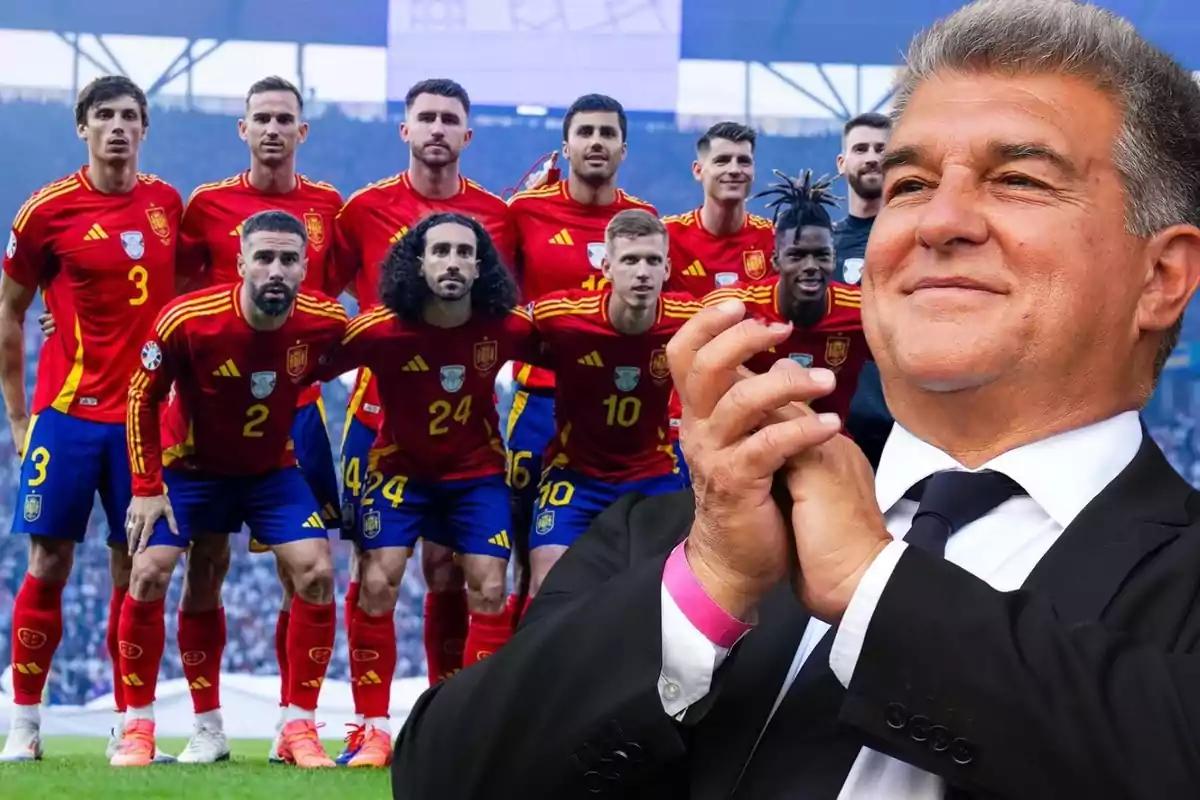 Un equip de futbol amb uniformes vermells posant per a una foto grupal mentre un home aplaudeix en primer pla.