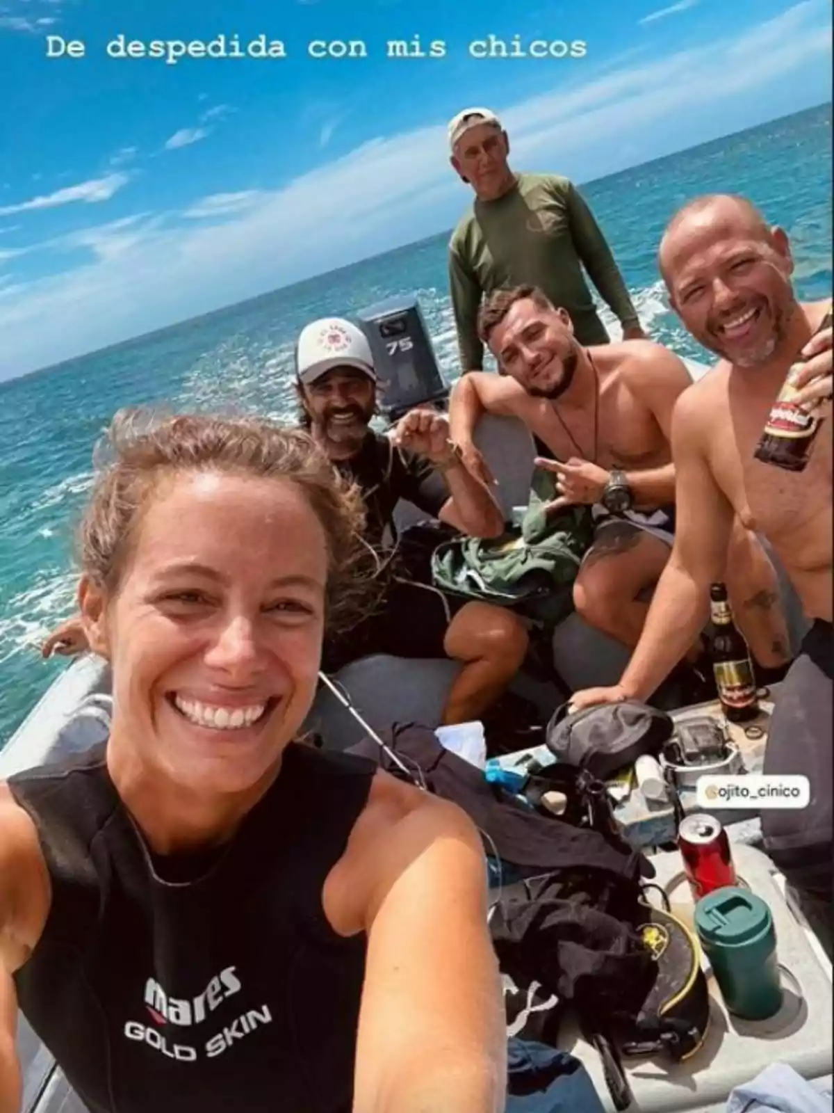 Captura de Laura Madrueño junto a un grupo de personas sonrientes en un bote en el mar, con equipo de buceo y bebidas.