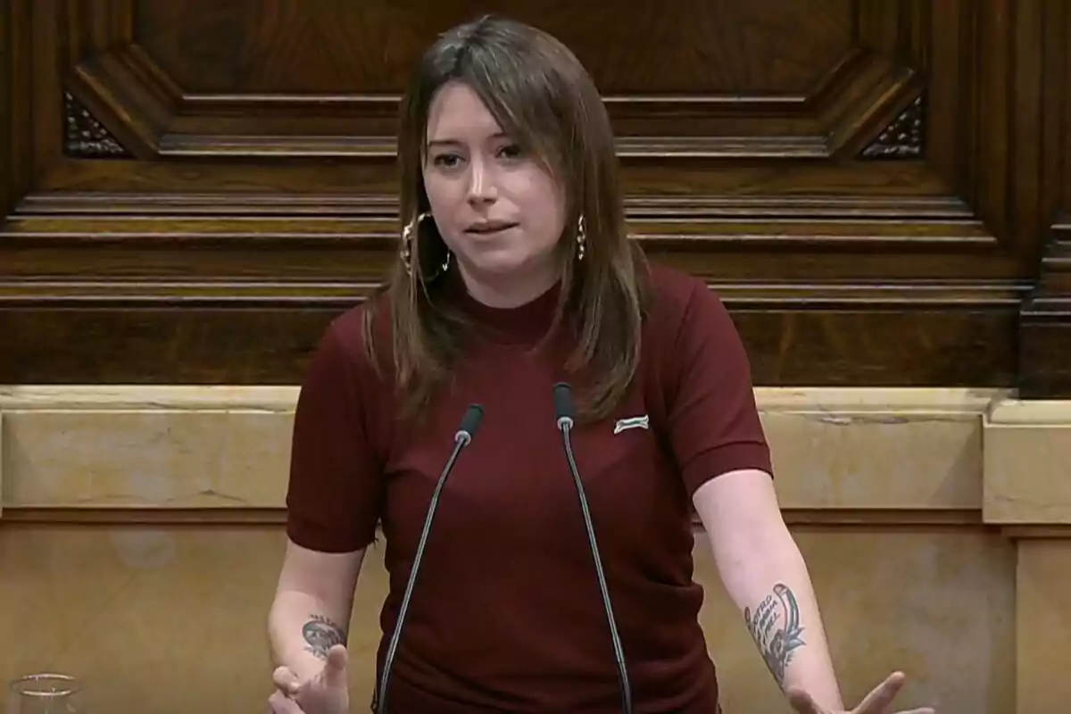 A person speaking at a podium with a wooden background.